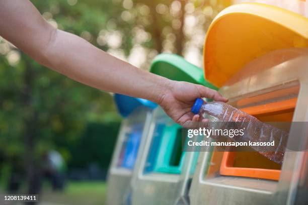close up hand throwing empty plastic bottle into the trash, recycling concept - garbage man stockfoto's en -beelden