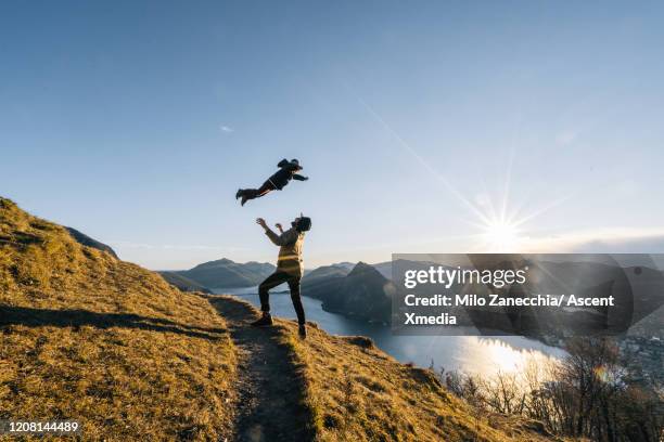 father and young son explore a mountain path above a lake at sunrise - connect friends sunrise photos et images de collection