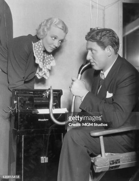 American actor Spencer Tracy plays a newspaper reporter using a dictaphone, as actress Virginia Bruce looks on, in a publicity still for 'The Murder...
