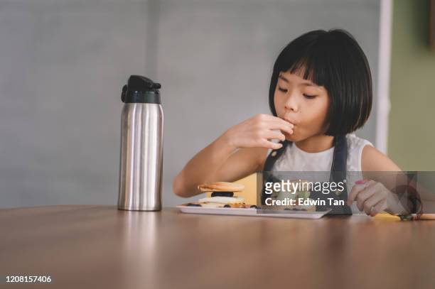 an asian chinese young girl eating and enjoying her home made breakfast pancake with blueberry