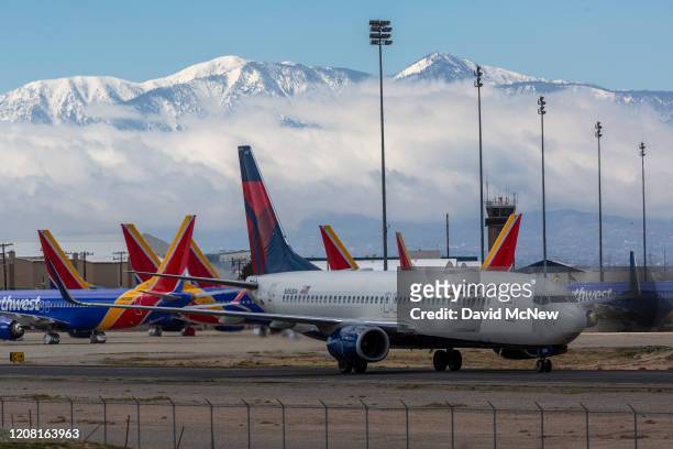 Delta Air Lines jet taxis passed Southwest Airlines jets to be parked with a growing number of jets at Southern California Logistics Airport on March...