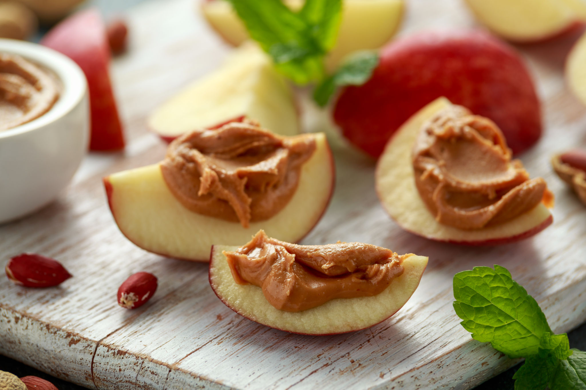 Peanut butter and apple to snack on white wooden board Peanut butter and apple to snack on white wooden board
