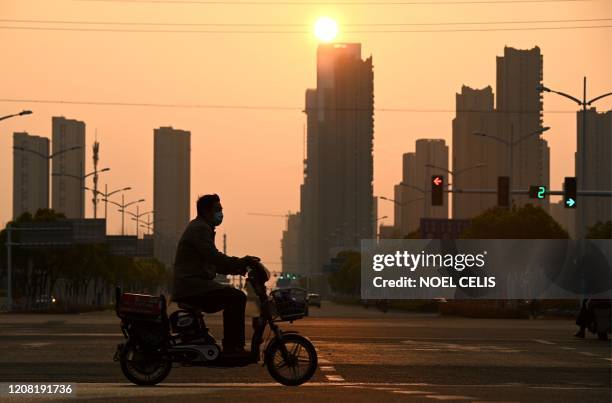 Man wearing a face mask drives his scooter along a street in Hefei, in Chinas eastern Anhui province on March 25, 2020.