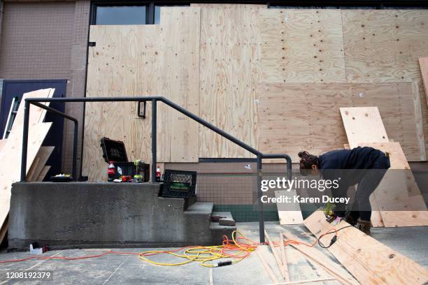 Construction worker Dani Harvey, from the property management company Blanton Turner, cuts plywood to board up the windows of an Urban Outfitters...