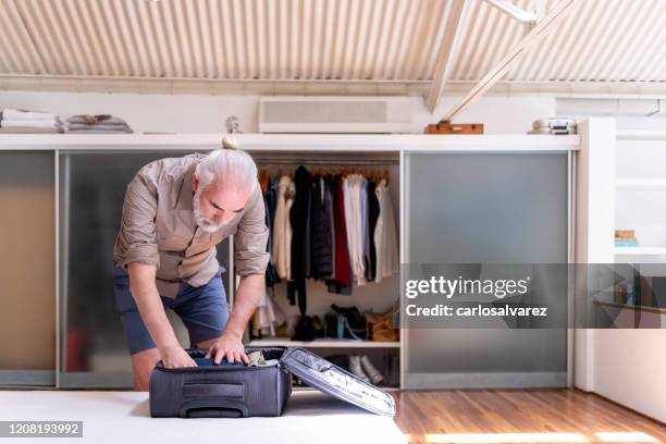 senior man packing luggage - carry on luggage stock pictures, royalty-free photos & images