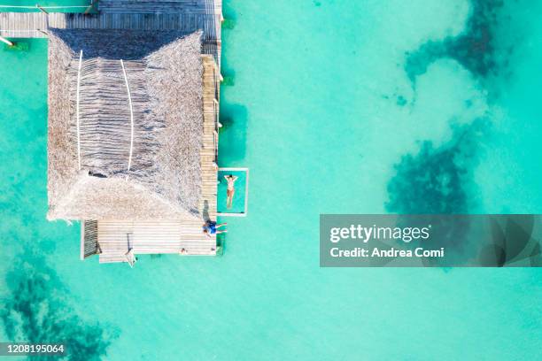 aerial view of two person relaxing on a overwater bungalow. bocas del toro, panama - thatched roof huts stock pictures, royalty-free photos & images