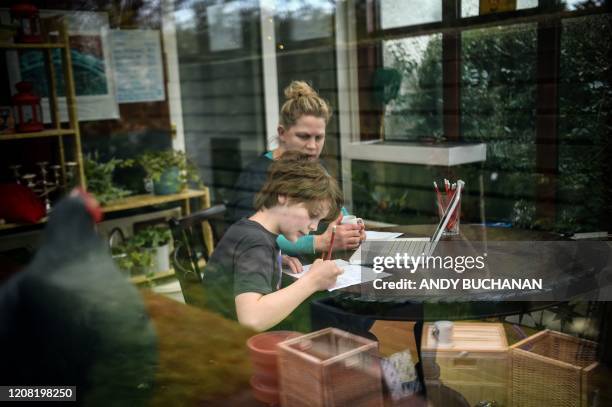 Year-old Lucas sits with his mother Fiona as she helps him with online lessons, set by his school following the national school closures due to the...