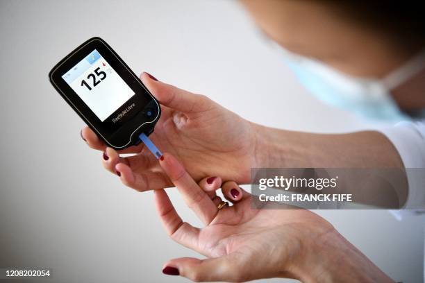 Woman with diabetes uses a glucometer to measure the glycemia in her blood in Paris on March 24 on the eighth day of a strict lockdown in France...