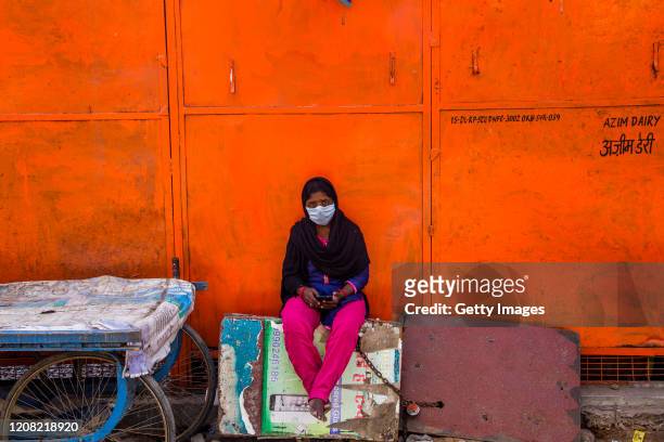 An Indian woman wearing a protective mask plays with her smart phone in a deserted commercial hub, as nationwide lockdown continues following the...
