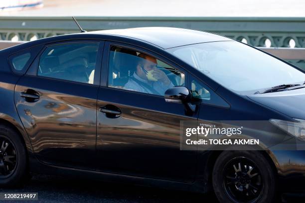 Man wears a mask as he drives along Westminster Bridge with the London Eye in the backgroud, in a near deserted central London on March 25 after...