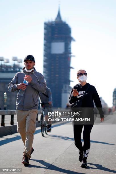 Pedestrians in masks walk along Westminster Bridge with Elizabeth Tower in the backgroud, in a quiet central London on March 25 after Britain's...
