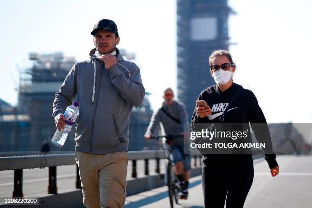 Pedestrians in masks walk along Westminster Bridge with Elizabeth Tower in the backgroud, in a quiet central London on March 25 after Britain's...