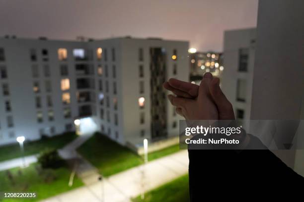 Young woman applauds from her window at the call every day at 8:00 p.m. To applaud as a tribute to the doctors and health workers who are working...