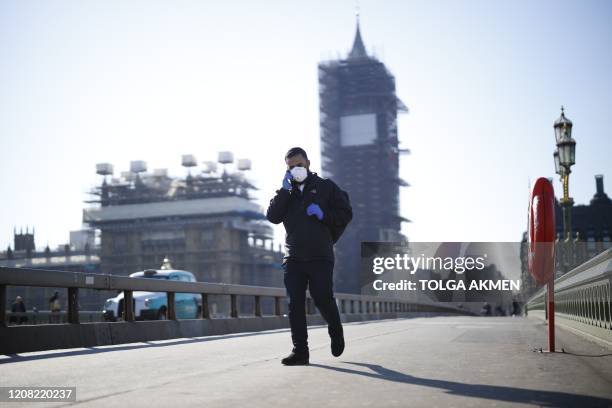 Pedestrian in a mask walk along Westminster Bridge with Elizabeth Tower in the backgroud, in a quiet central London on March 25 after Britain's...