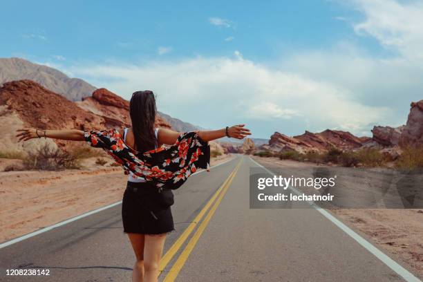 mujer por el camino rural vacío en argentina - salta argentina fotografías e imágenes de stock