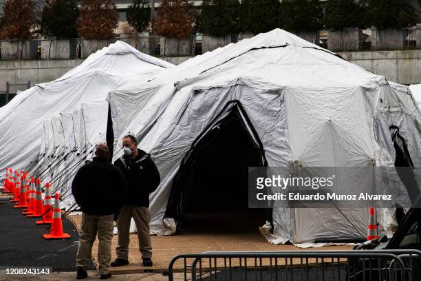 People speak near a makeshift morgue outside of Bellevue Hospital on March 25, 2020 in New York City, New York. Across the country schools,...