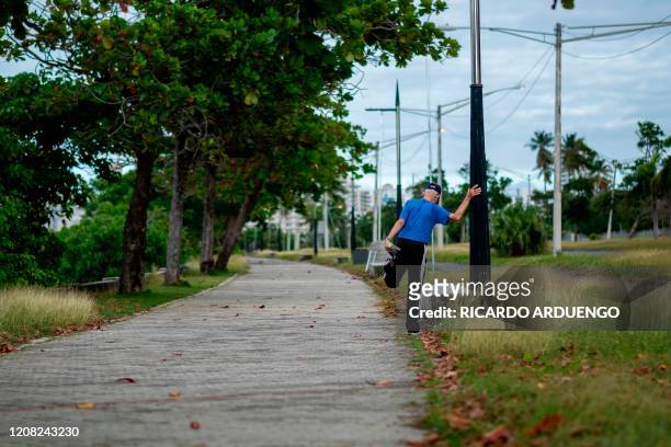 An elderly man stretches while exercising in San Juan, Puerto Rico on March 25, 2020. - Almost one billion people were confined to their homes...