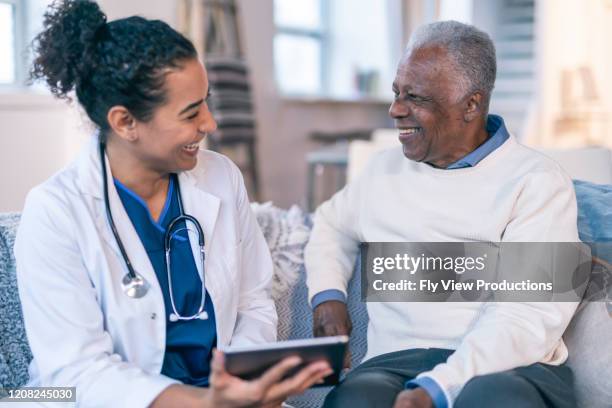 female doctor meeting with senior patient in his home - electronic medical record stock pictures, royalty-free photos & images