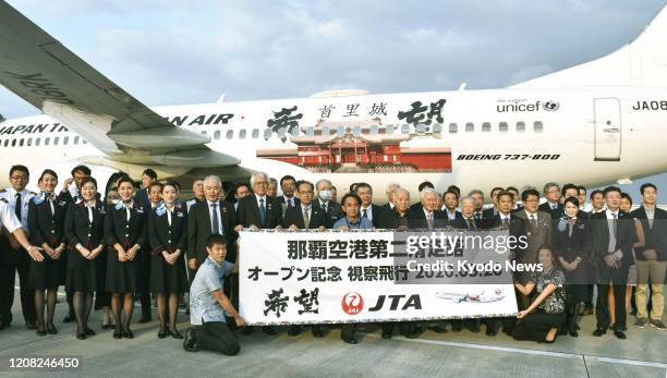 Okinawa prefectural officials and Japan Transocean Air Co. Staff pose for a photo at Naha airport on March 26 marking the opening of the southern...