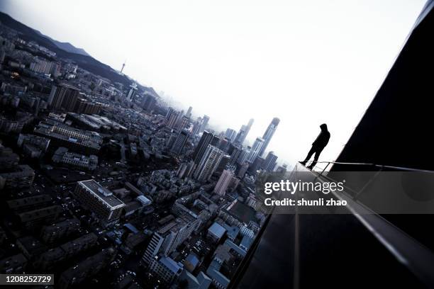 a young man standing on the rooftop overlooking the city - skyscraper roof stock pictures, royalty-free photos & images