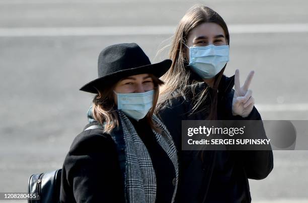 Two girls wearing protective face masks react as they walk in the center of Ukrainian capital of Kiev on March 26 amid concerns over the spread of...