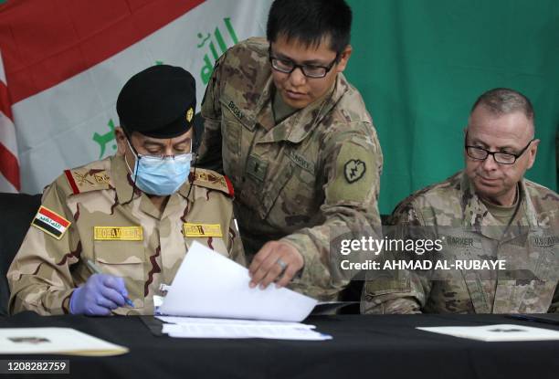 Coalitions Brigadier General Vincent Barker watches Iraqs Staff Major General Mohammad Fadhel Abbas sign a document during a pullout ceremony at the...