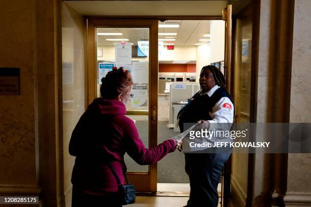 Security guard hands out a instruction sheet outside of a State of Michigan Unemployment Agency office in Cadillac Place that is currently closed do...