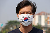 South Korea flag on hygienic mask. Masked Asian man prevent germs. concept of Tiny Particle protection.