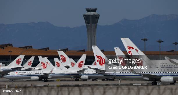 Air China planes are seen parked on the tarmac at Beijing Capital Airport on March 27, 2020. - China will drastically cut its international flight...