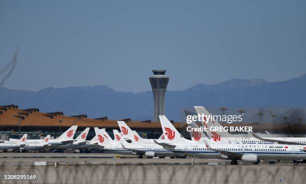 Air China planes are seen parked on the tarmac at Beijing Capital Airport on March 27, 2020. - China will drastically cut its international flight...