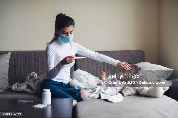 a mother measure temperature on her sick child at home. - child coronavirus sick stock pictures, royalty-free photos & images