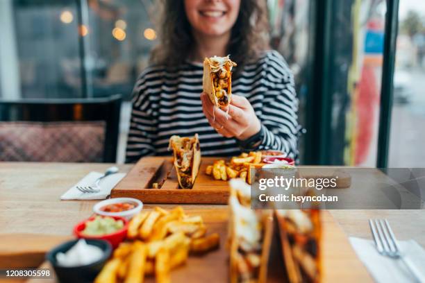 frau essen taco - wrap sandwich stock-fotos und bilder