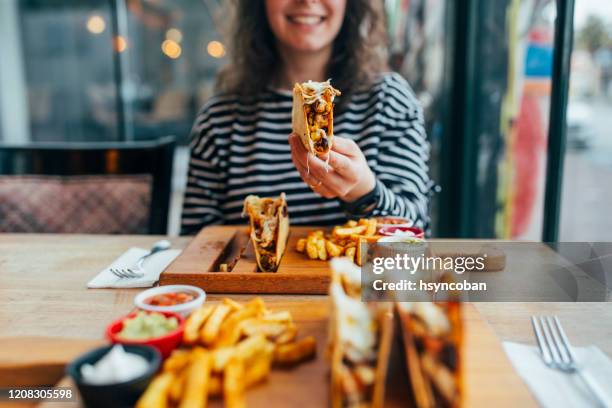 mujer comiendo taco - taco fotografías e imágenes de stock