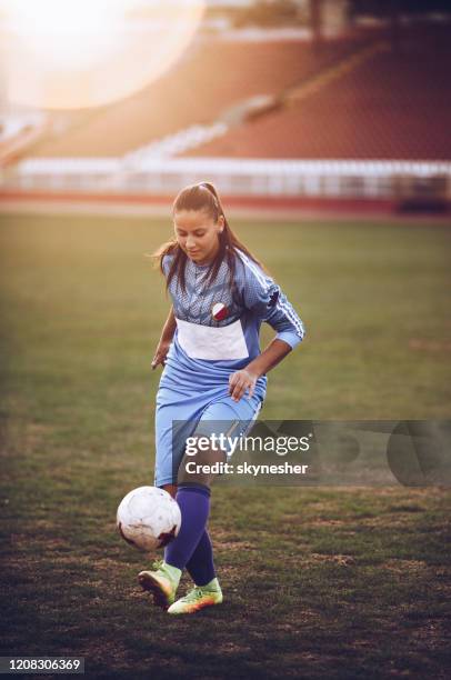 female soccer player practicing with ball on the field. - soccer skills stock pictures, royalty-free photos & images