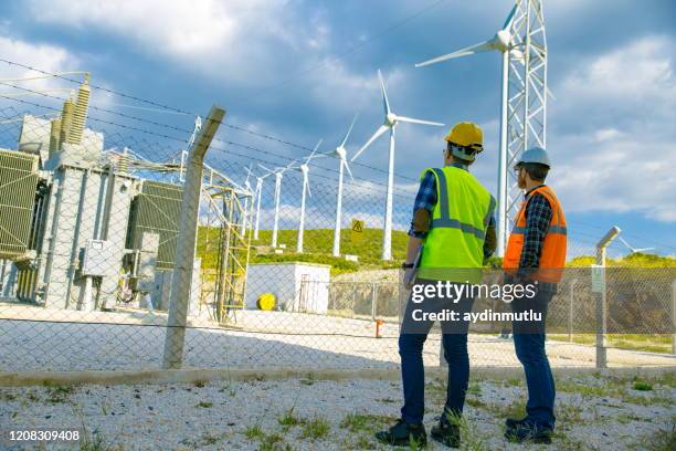 若い労働者を探して、フィールドでの風力タービンをチェック - transformer ストックフォトと画像