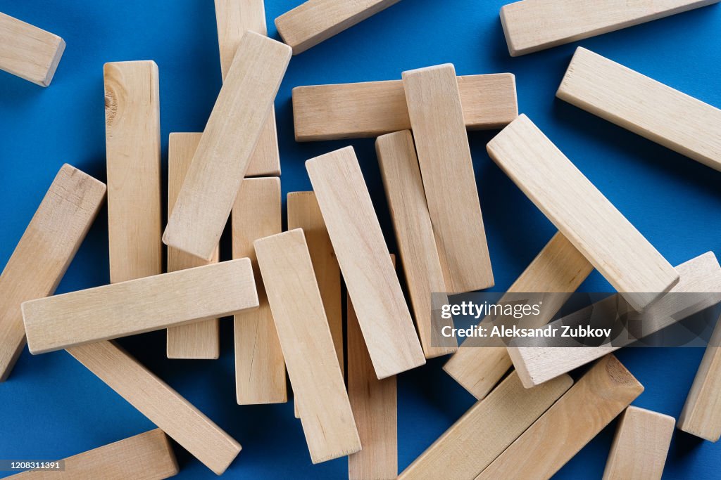 A Pile Of Scattered Wooden Blocks On A Blue Background. Construction Game. The broken tower.
