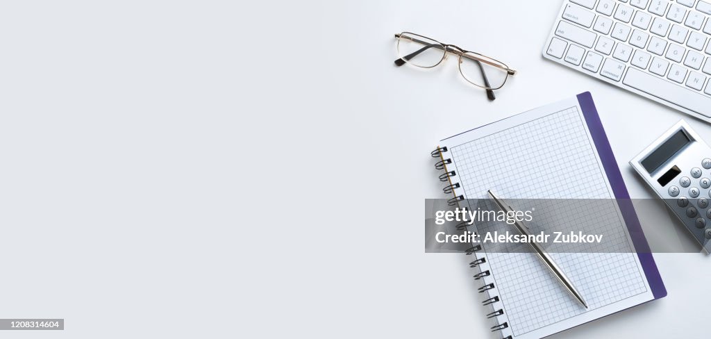 The Pen Is On An Open Notepad. Next To The Calculator, Glasses And Laptop. A Blank Sheet Of Notebook With The Items Of A Businessman Or Accountant. Concept Of Financial Reporting. Banner.