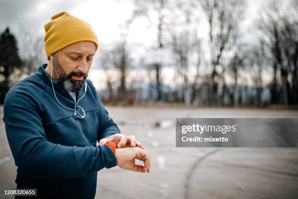mature men running and using smart watch outdoors - fitness tracker stock pictures, royalty-free photos & images