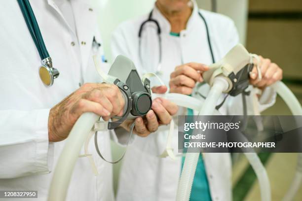 twee onherkenbaar medisch personeel dat twee ademhalingsmaskers houdt - ventilator stockfoto's en -beelden