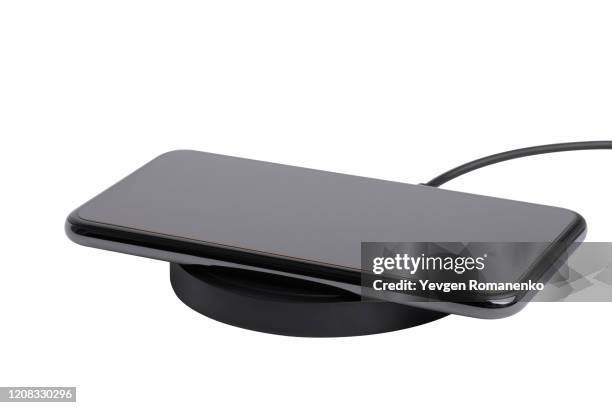 wireless charger with mobile phone isolated on white background - wireless charging stock-fotos und bilder