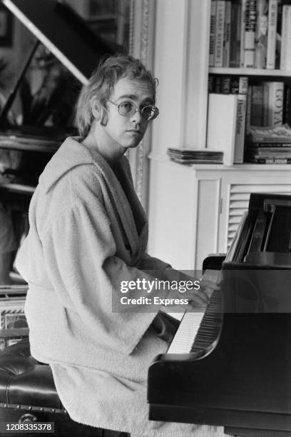 English singer, songwriter, pianist, and composer Elton John, wearing bathrobe, play the piano at his home, UK, 16th March 1973.