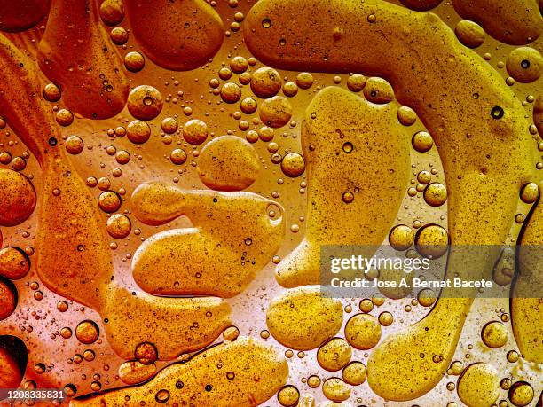 full frame of abstract shapes and textures formed of bubbles and drops oil stains on a gold colored liquid background. - lubrication stock pictures, royalty-free photos & images