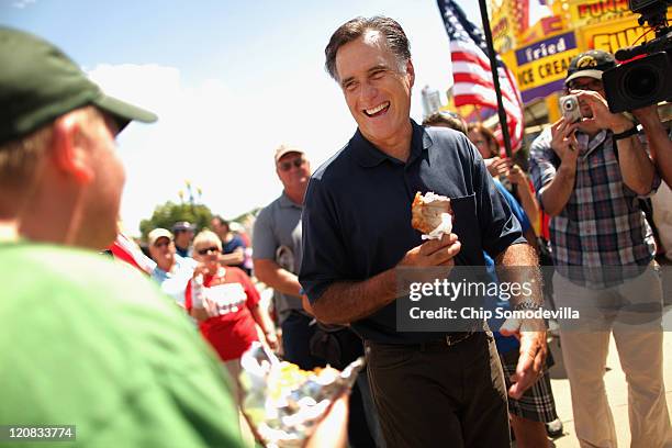 Republican presidential candidate Mitt Romney eats a pork chop on a stick while talking with voters at the Iowa State Fair August 11, 2011 in Des...