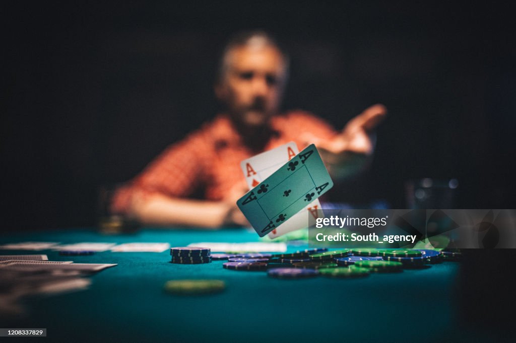 Hombre maduro lanzando cartas de juego en la mesa