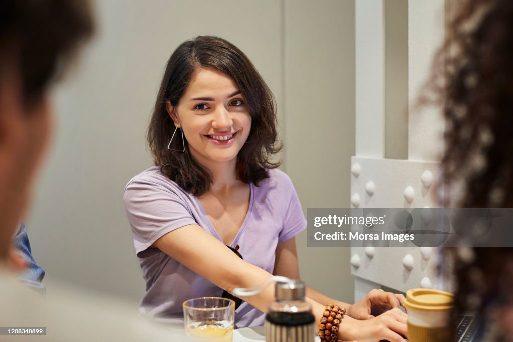 Happy young woman with friends at table in hostel