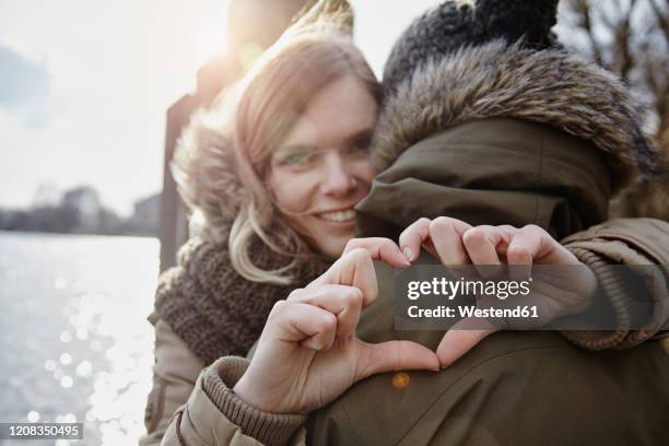 happy young woman forming heart with her hands - young love stock-fotos und bilder