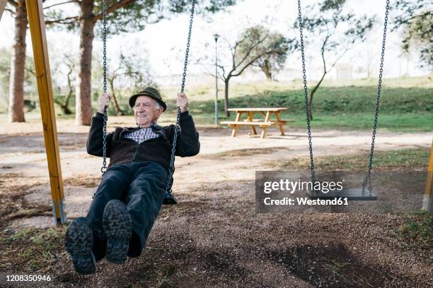old man swinging on playground in park - schaukel mann stock-fotos und bilder
