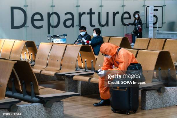 Man wearing a protective suit sits at the departure hall. Number of Incheon Airport passengers falls to record low amid coronavirus spread.