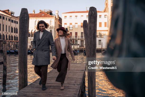 young couple walking on a jetty at the canal grande in venice, italy - venice couple foto e immagini stock