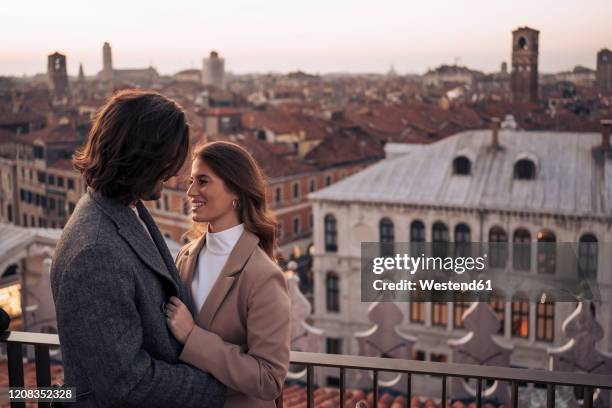 happy young couple on a balcony above the city of venice, italy - venice couple fotografías e imágenes de stock